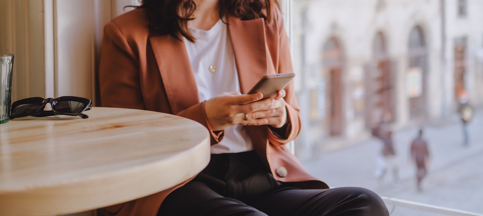 Sitting at table by window holding phone