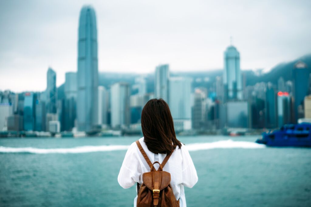 Woman with brown backpack looking over cityscape