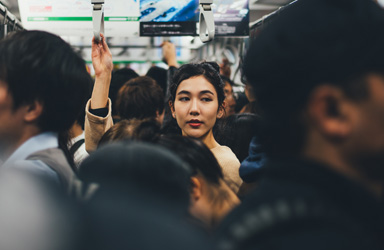 Focus on commuter holding hand strap on busy train