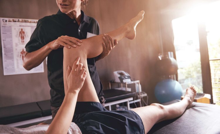 Person receiving physiotherapy from female physiotherapist in treatment room