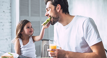 Daughter feeds dad a sandwich 