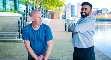 Two men stretch by the river during exercise