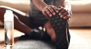 Close up image of person sitting on the floor and stretching leg after exercise