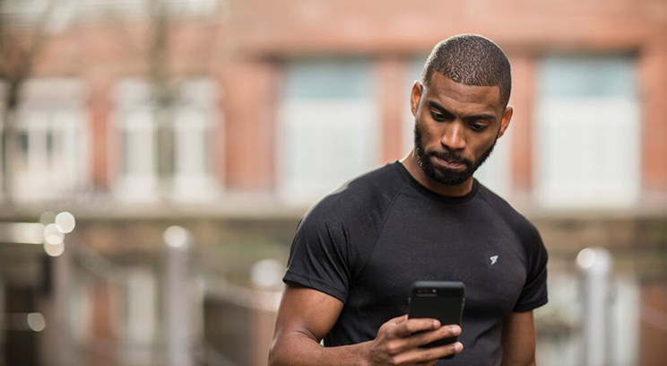 Young athletic black male checks his phone